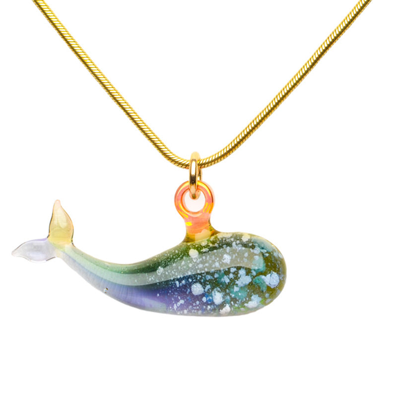 A blue/green ash-infused cremation pendant on a gold chain features a graceful whale silhouette in glass, symbolizing strength and wisdom.