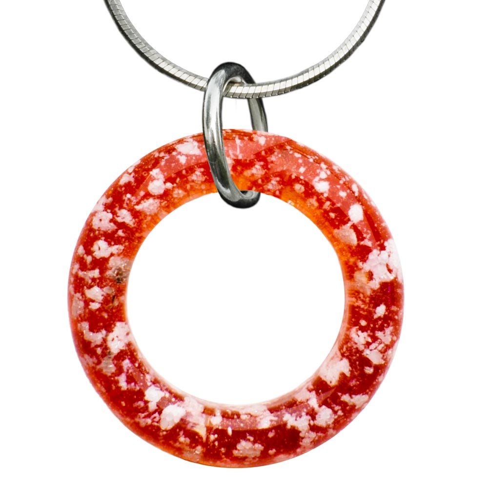 An image showing a Ruby Halo Ashes Pendant, a glass pendant infused with a small portion of ashes. The pendant is circular in shape, approximately 1.25" in diameter. It features vibrant colors and a delicate, handmade design. The pendant is suspended from a chain, which adds to its overall elegance. The image captures the personalized and heartfelt nature of the pendant, symbolizing the cherished memories and connection to a beloved person or pet.